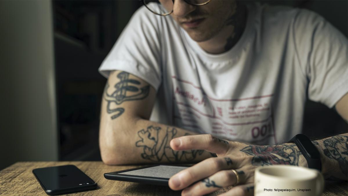 Henkilö lukee e-kirjaa pöydän ääressä.