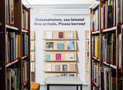 Kirjahyllyjä, seinällä teksti "Uutuusaineistoa, saa lainata!".